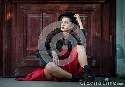 Young beautiful brunette woman with red short dress and black hat posing sensual in vintage scenery. Romantic mysterious lady Stock Photo