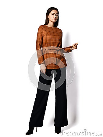 Young beautiful brunette woman in stylish business trousers and shirt and black high heel boots standing over white background Stock Photo