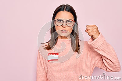 Young beautiful brunette woman wearing sticker with hello my name is message annoyed and frustrated shouting with anger, yelling Stock Photo