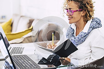 Young beautiful business woman smile and work with two different laptop - modern alternative office at home for independent people Stock Photo