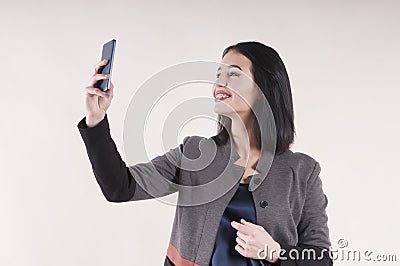 Young beautiful businesswoman portrait cheerful phone smiling braces studio, making selfie Stock Photo