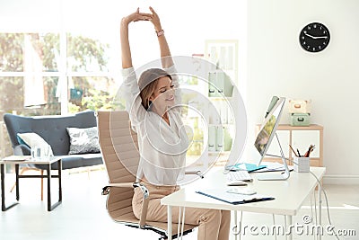 Young beautiful businesswoman stretching in office. Stock Photo