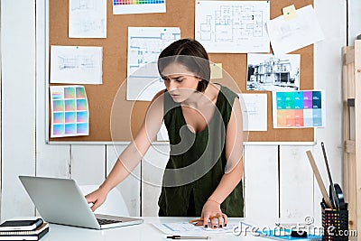 Young beautiful businesswoman working with drawings at workplace. Office background. Stock Photo