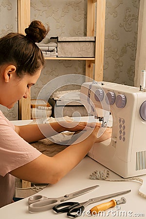 Beautiful caucasian woman sews on a sewing machine, hobby and sewing production concept Stock Photo