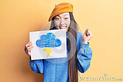 Young beautiful chinese woman holdig cloud and thunder draw screaming proud, celebrating victory and success very excited with Stock Photo