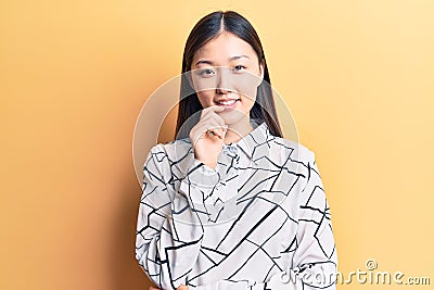Young beautiful chinese woman wearing elegant shirt smiling looking confident at the camera with crossed arms and hand on chin Editorial Stock Photo