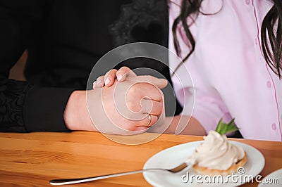 Young beautiful couple is holding each other`s hands in a cafe. Stock Photo