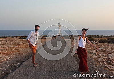 Young beautiful couple`s portrait with Cap de Barberia`s lighthouse on soft background, Formentera, Balearic Islands, Spain Stock Photo