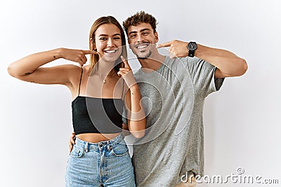 Young beautiful couple standing together over isolated background smiling cheerful showing and pointing with fingers teeth and Stock Photo