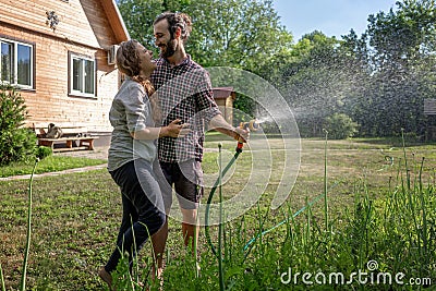 Young beautiful couple watering the plants in a country house, summer, work in the garden, love and summer concept Stock Photo