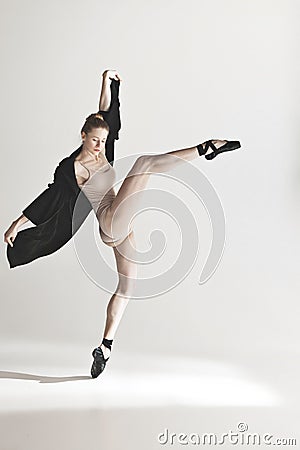 Young beautiful dancer in beige swimsuit dancing on gray background Stock Photo