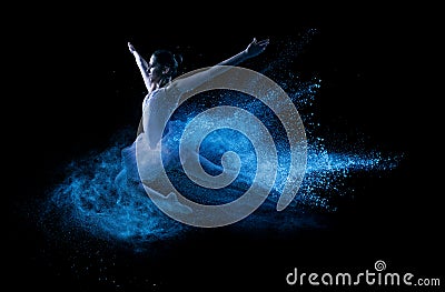 Young beautiful dancer jumping into blue powder cloud Stock Photo