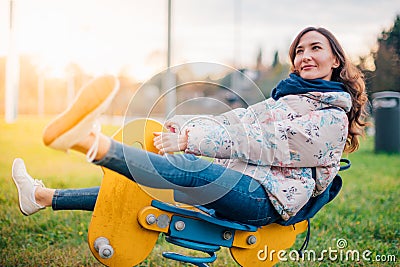 Young beautiful dreaming woman playing riding with rocking spring horse Stock Photo