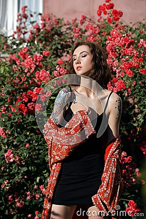 Young beautiful dreamy woman with closed eyes in rose garden. Outdoor portrait of a romantic girl with hard light Stock Photo