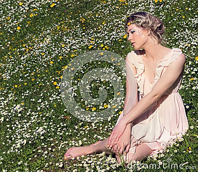 Young beautiful elegant, attractive girl standing in a forest near flowering tree with long hair blond in Sunny day and makeup Stock Photo