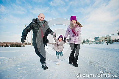 Young beautiful family in bright clothes winter fun jumping and running, snow, lifestyle, winter holidays Stock Photo