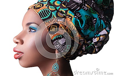 Young beautiful fashion model with traditional african style with scarf, earrings and makeup on orange background. Stock Photo