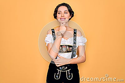 Young beautiful german woman with blue eyes wearing traditional octoberfest dress with hand on chin thinking about question, Stock Photo