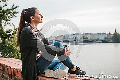 Young beautiful girl on the bank of the Vltava river in Prague in the Czech Republic, admiring the beautiful view and Stock Photo