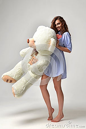 Young beautiful girl with big teddy bear soft toy happy smiling Stock Photo