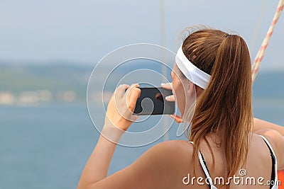 A young beautiful girl with a brown-haired woman takes a photo of a smartphone on the sea from the side of a sailing yacht. A fasc Editorial Stock Photo