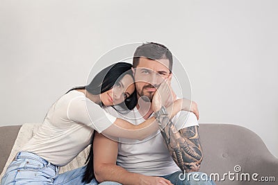 A young beautiful girl is comforting her boyfriend who is sitting disappointed. He lost his job and is sad Stock Photo