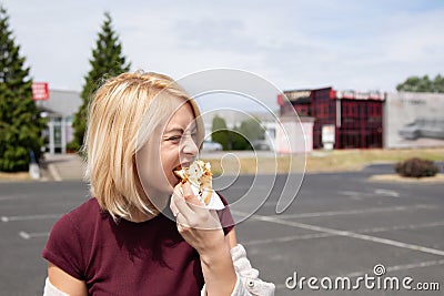 A young woman holds a bitten hot dog Stock Photo