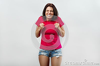 A young, beautiful girl experiences anger, anger, hatred. Isolated on a light background. Different human emotions, feelings of Stock Photo