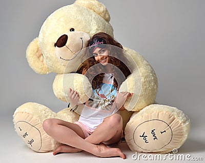 Young beautiful girl hugging big teddy bear soft toy happy smiling Stock Photo