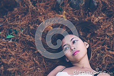 Young beautiful girl laying on the forest floor, with hair tangled in small branches that felled from pine trees, fashion concept Stock Photo