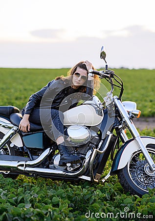 Young beautiful girl in leather clothes posing on a motorcycle Stock Photo