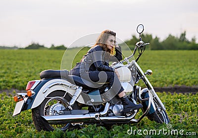 Young beautiful girl in leather clothes posing on a motorcycle Stock Photo