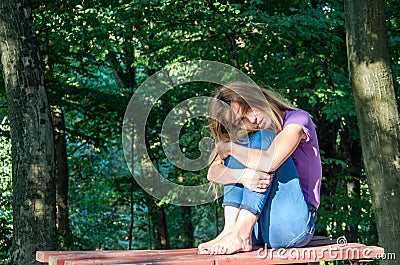 Young beautiful girl model in jeans and a T-shirt with long blond hair and sad smiles pensively posing for a walk in the autumn pa Stock Photo