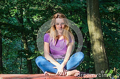 Young beautiful girl model in jeans and a T-shirt with long blond hair and sad smiles pensively posing for a walk in the autumn pa Stock Photo