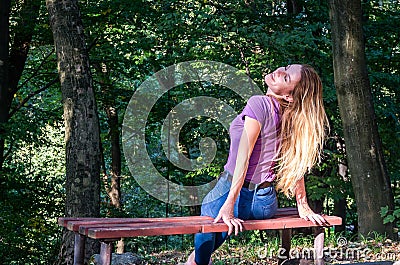 Young beautiful girl model in jeans and a T-shirt with long blond hair and sad smiles pensively posing for a walk in the autumn pa Stock Photo