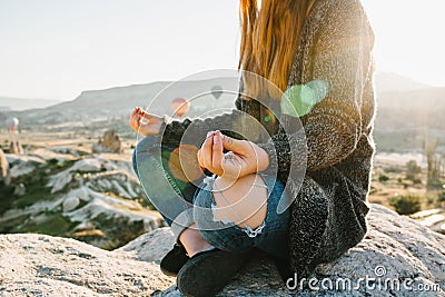 Young beautiful girl practicing yoga at the top of a mountain in Cappadocia at sunrise. Practices of relaxation. Stock Photo