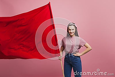 Young and beautiful girl with a red flag on a pink background. A socially active woman, to protest and fight for rights Stock Photo