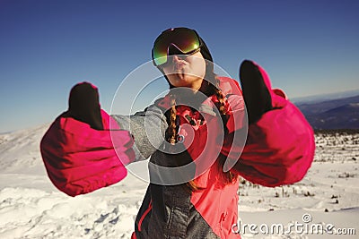 Young beautiful girl snowboarder with mask on her face holds thumbs up Stock Photo