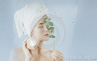 A young girl after taking a bath uses a moisturizing body and face cream on a blue background. The concept of skin care Stock Photo