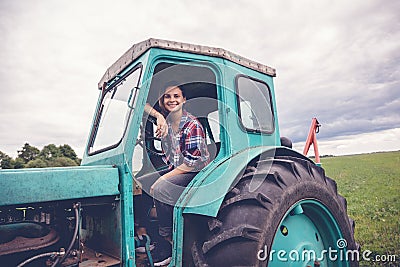 Young beautiful girl working on tractor in the field, unusual work for women, gender equality concept Stock Photo