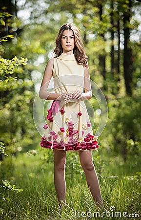 Young beautiful girl in a yellow dress in the woods. Portrait of romantic woman in fairy forest. Stunning fashionable teenager Stock Photo