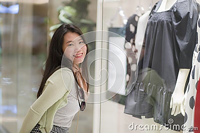 Young beautiful and happy Asian buying at shopping mall - young attractive and stylish Korean woman holding shopping bags at Stock Photo