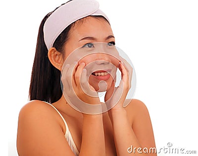 Young beautiful and happy Asian Korean woman applying skincare wrinkle prevention treatment or aging beauty product on her face in Stock Photo