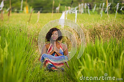 Young beautiful and happy black African American woman sitting at rive field outdoors practicing yoga relaxation and meditation Stock Photo