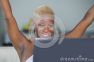 Young beautiful happy black afro American woman smiling working on laptop computer at home relaxed on sofa couch celebrating succe Stock Photo