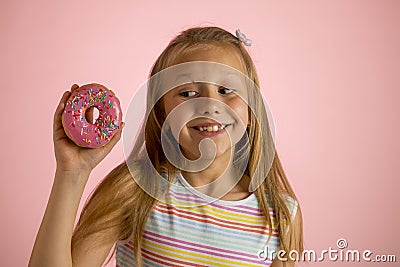 Young beautiful happy and excited blond girl 8 or 9 years old holding donut desert on her hand looking spastic and cheerful in sug Stock Photo