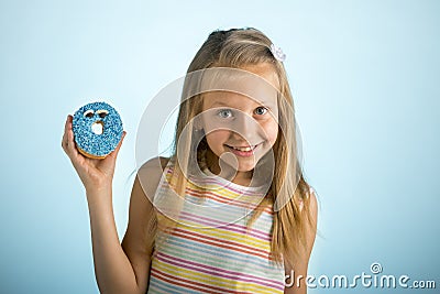 Young beautiful happy and excited blond girl 8 or 9 years old holding donut desert on her hand looking spastic and cheerful in sug Stock Photo