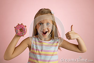 Young beautiful happy and excited blond girl 8 or 9 years old holding donut desert on her hand looking spastic and cheerful in sug Stock Photo