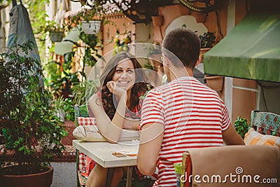 Young beautiful happy loving couple sitting at street open-air cafe looking at each other. Beginning of love story. Relationship Stock Photo