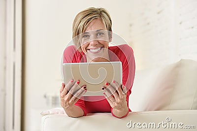 Young beautiful happy 30s woman smiling using digital tablet pad at home living room couch Stock Photo